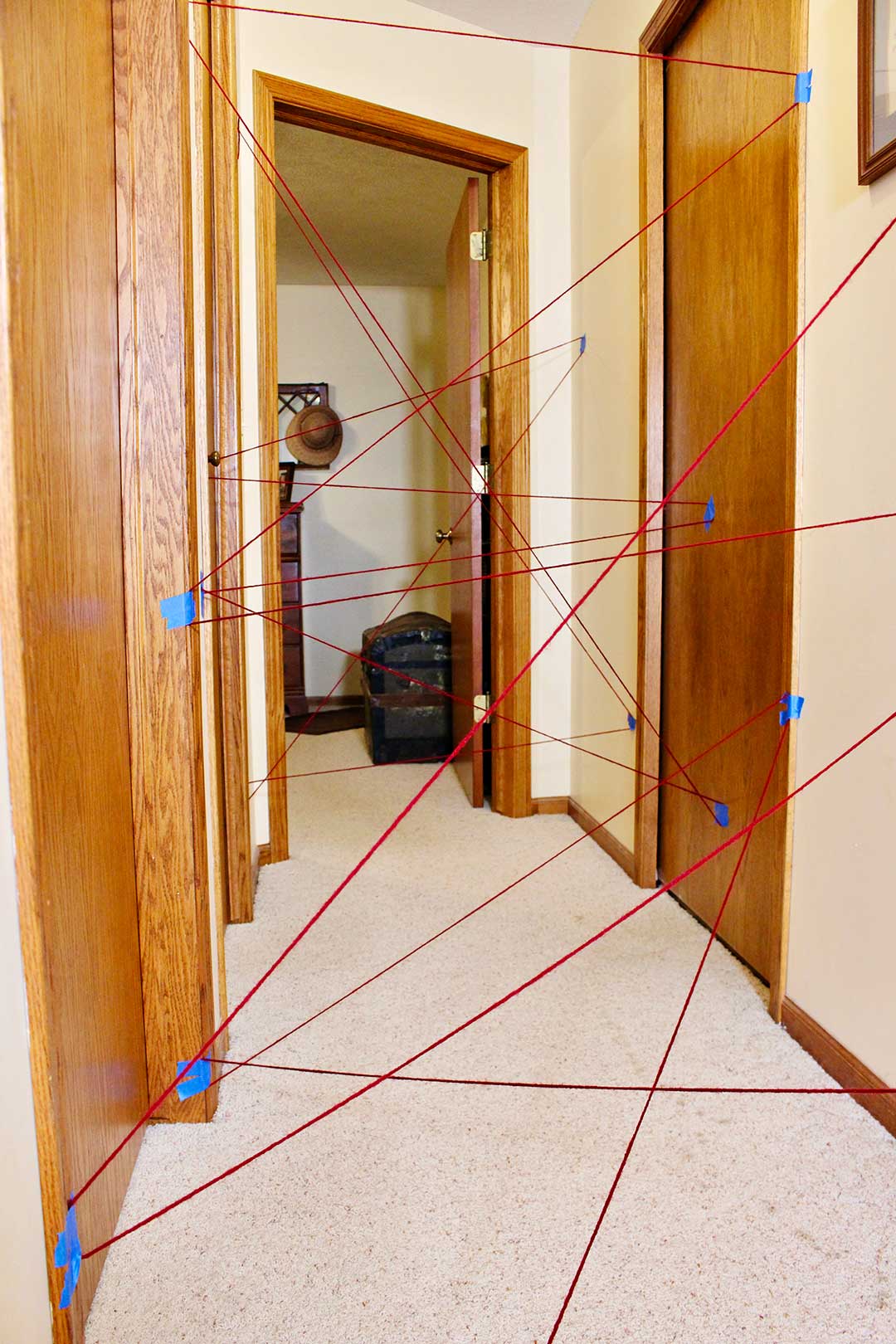 View of completed DIY Laser Maze in a hallway with off white carpet and wooden doors.