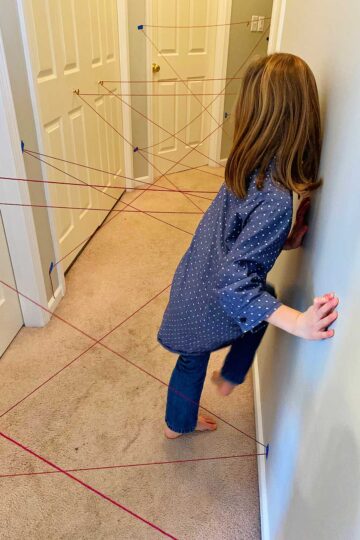 A girl in a polka dotted blue shirt and jeans going through the maze.