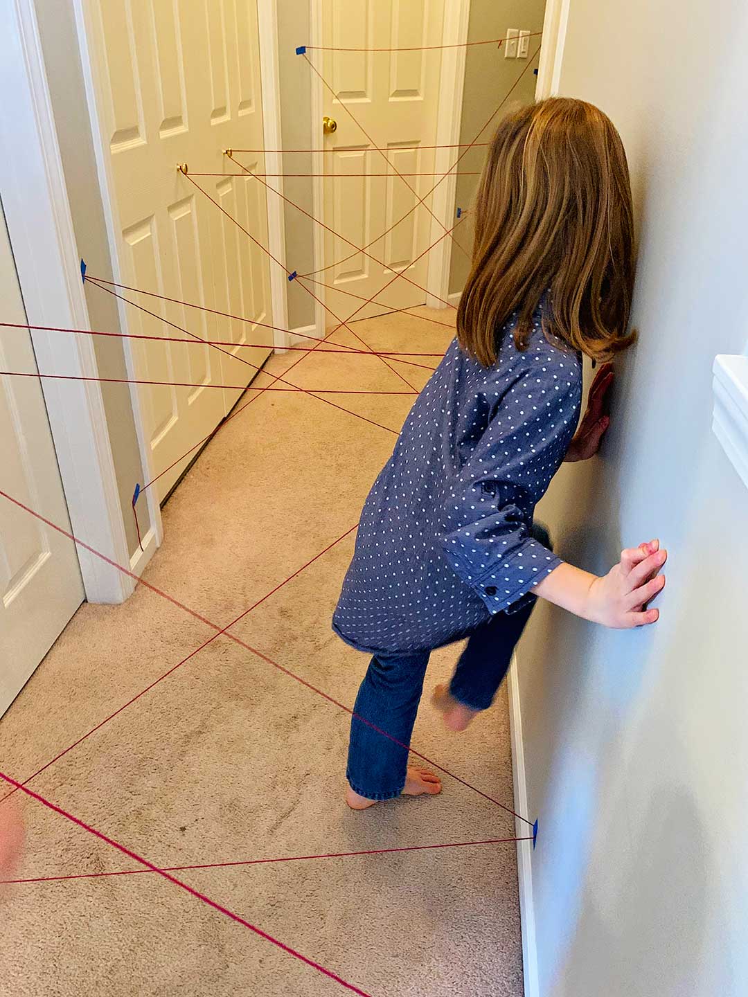 A girl in a polka dotted blue shirt and jeans going through the maze.