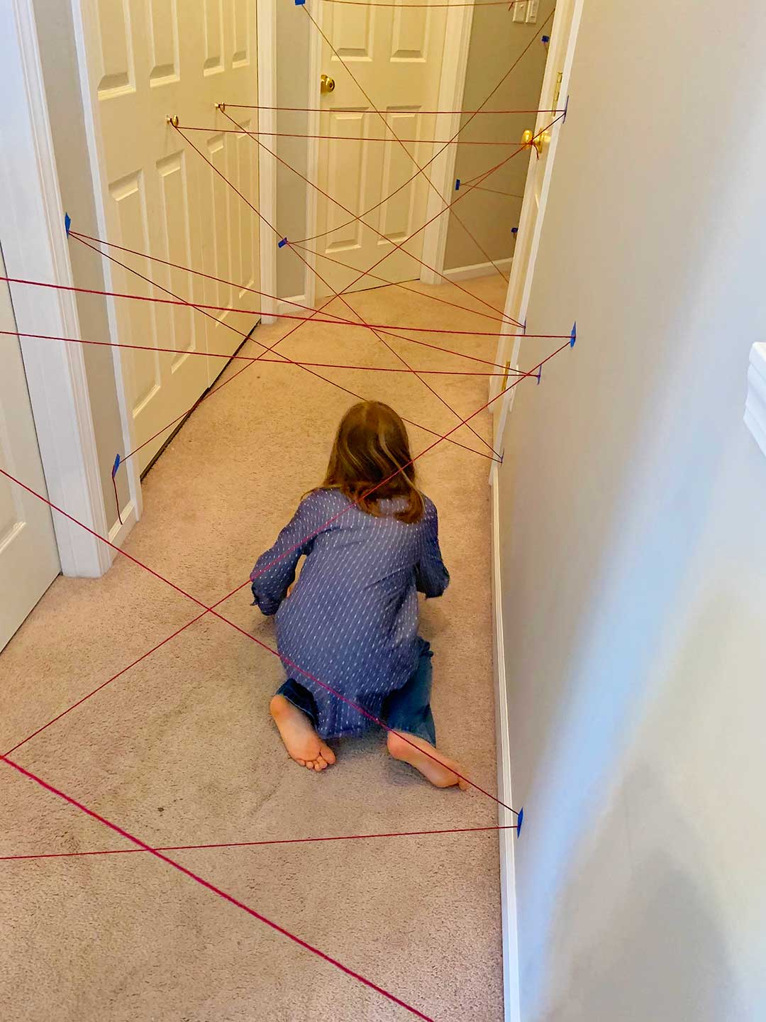 A girl in a polka dotted blue shirt and jeans going through the maze on hands and knees.