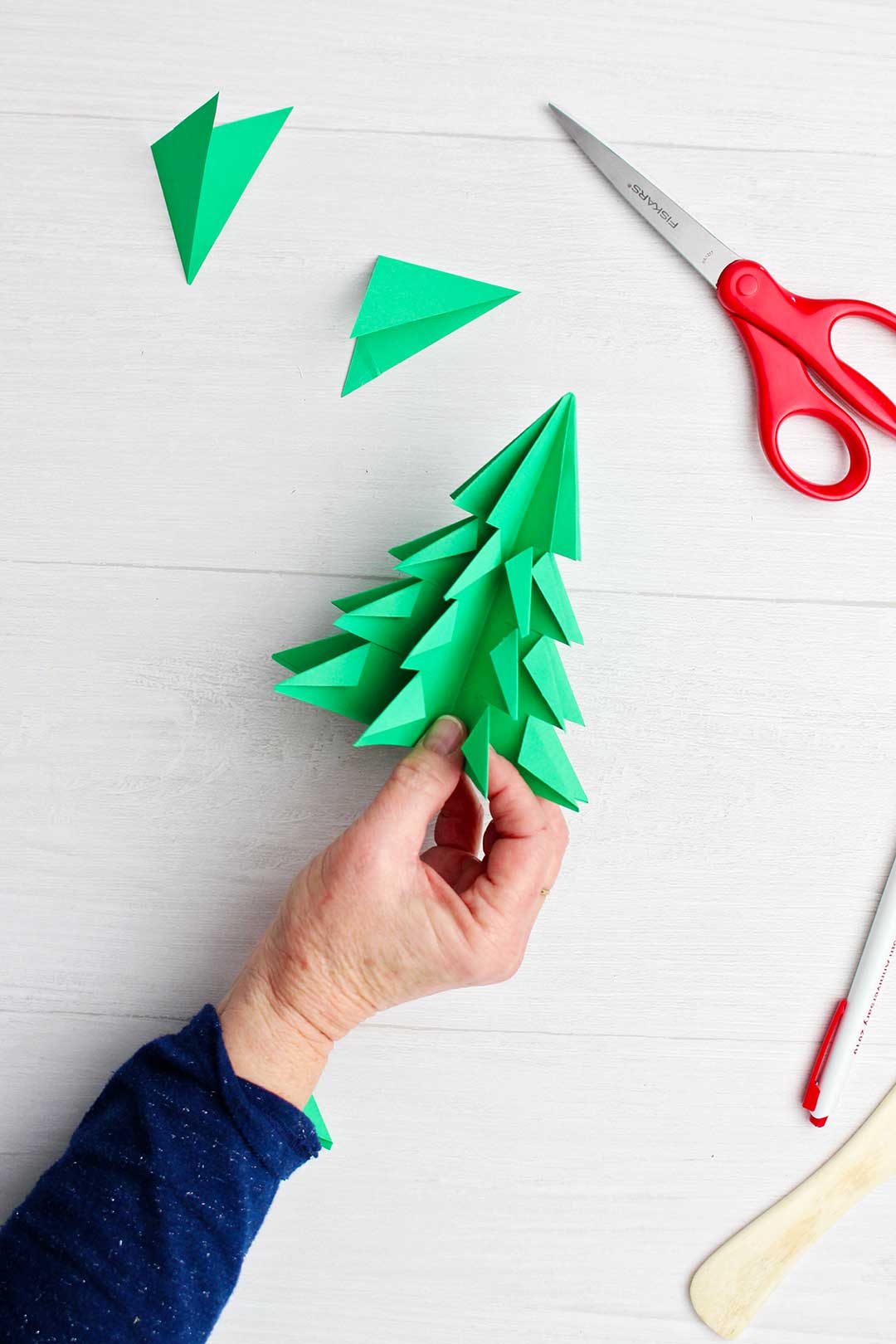 Completed green paper origami tree with scissors near by.
