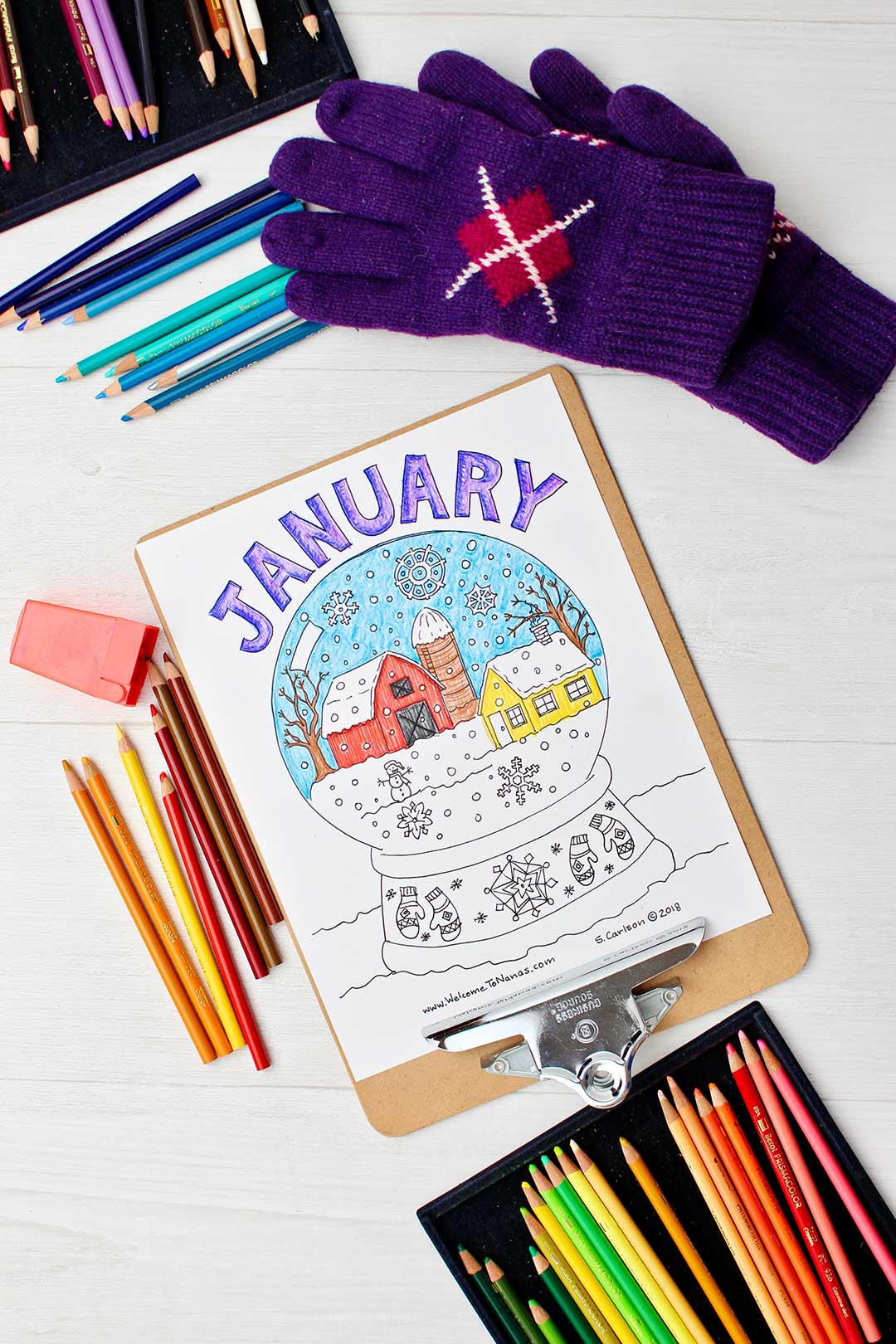 Completed January coloring page on clipboard surrounded by colored pencils and purple gloves.