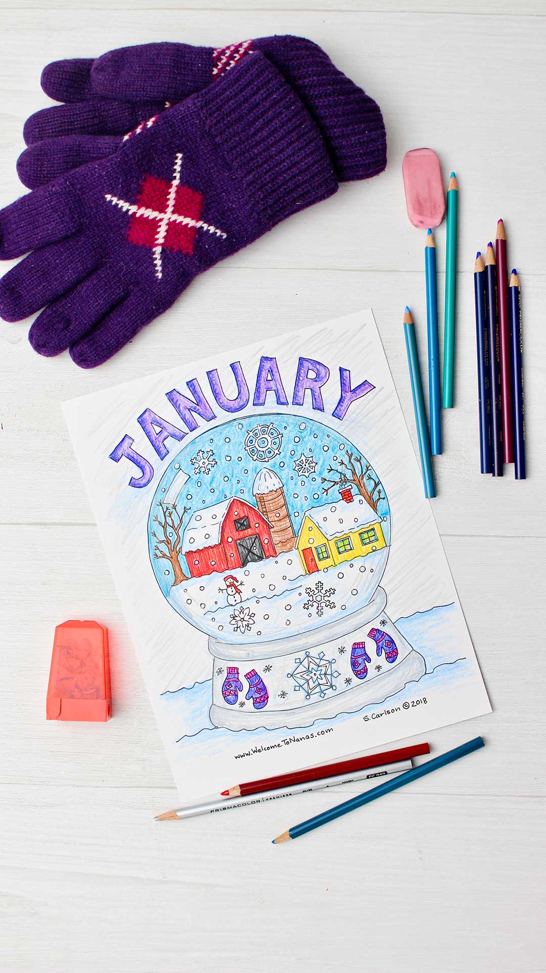 Completed January coloring page surrounded by colored pencils, pink eraser, pencil sharpener and purple gloves.
