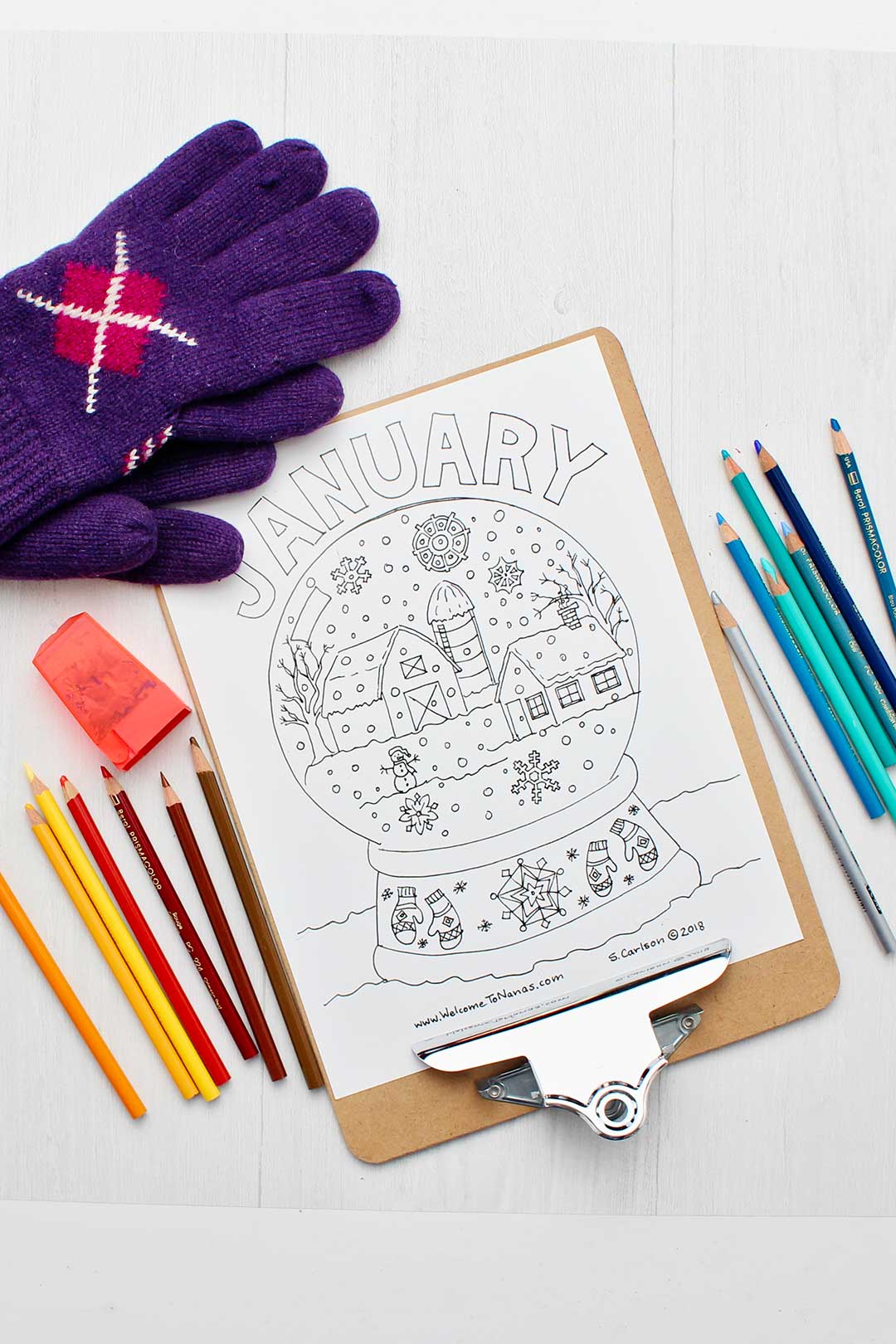 Uncolored January coloring page on clipboard surrounded by colored pencils and purple gloves.