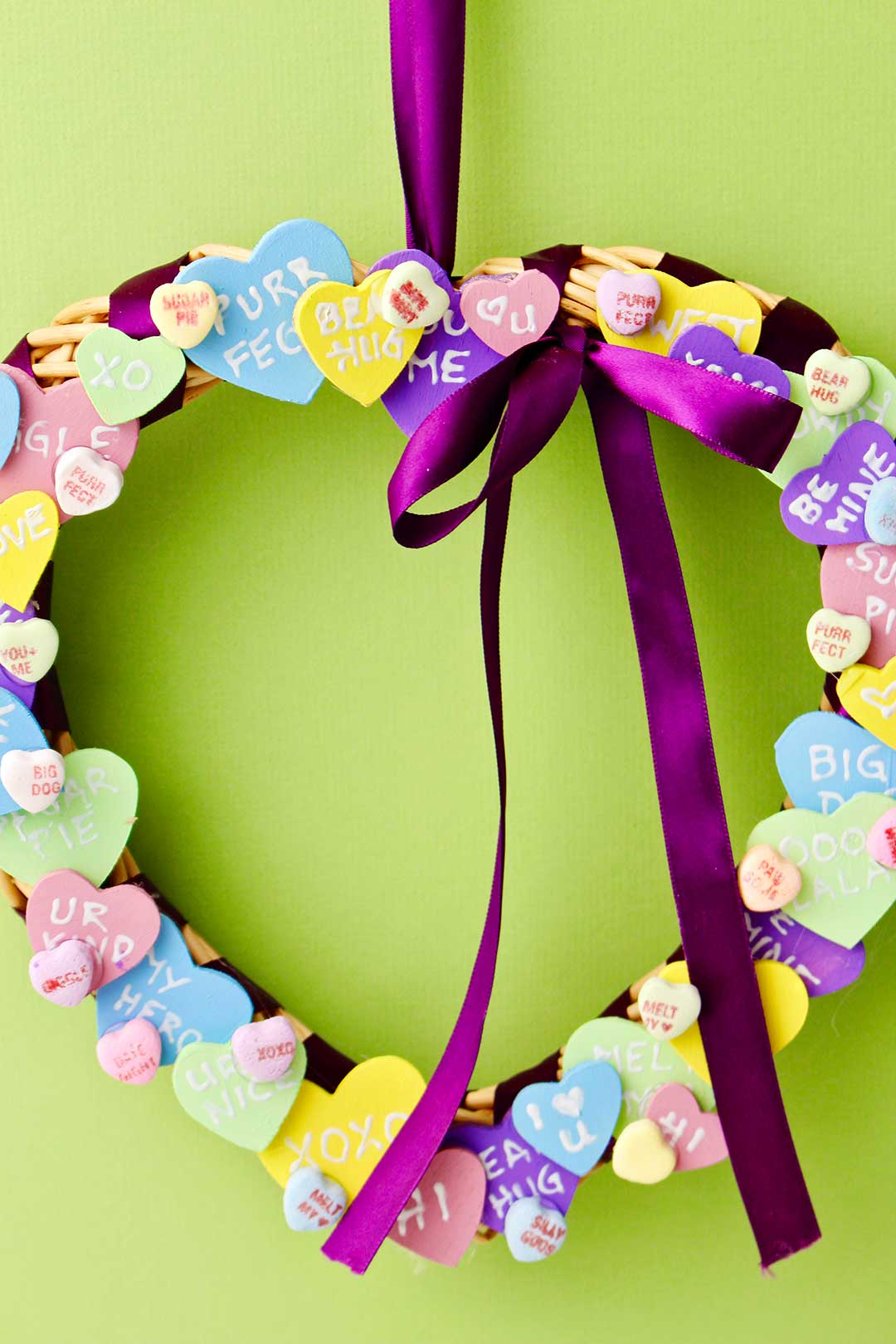 Completed Conversation Heart Wreath hung against a celery green backdrop.
