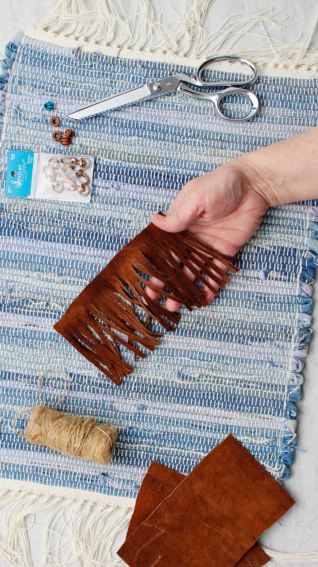 Hand holding strip of brown leather which was cut into having fringe.