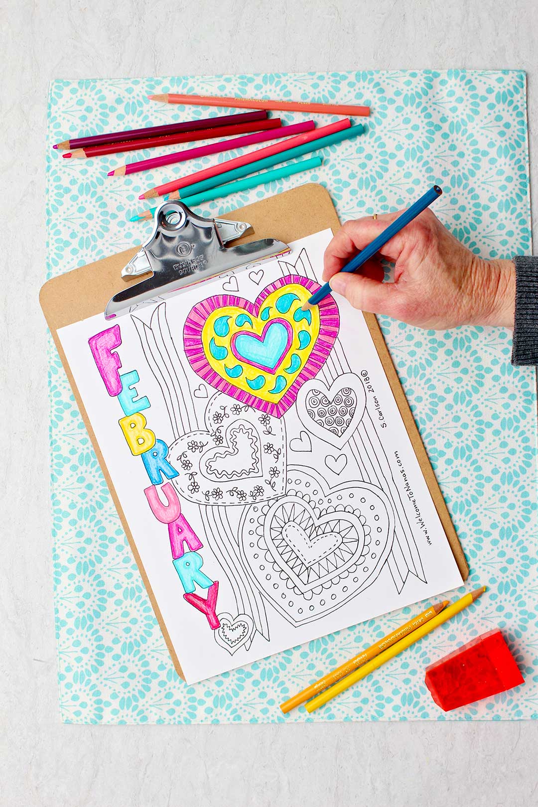 Hand coloring details inside of a heart blue on February coloring page.