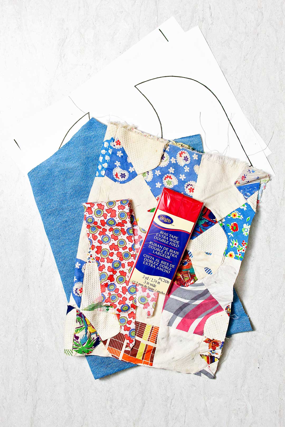 Supplies to make reversible baby bibs. Blue fabric, patchwork fabric, bias tape and patterns.