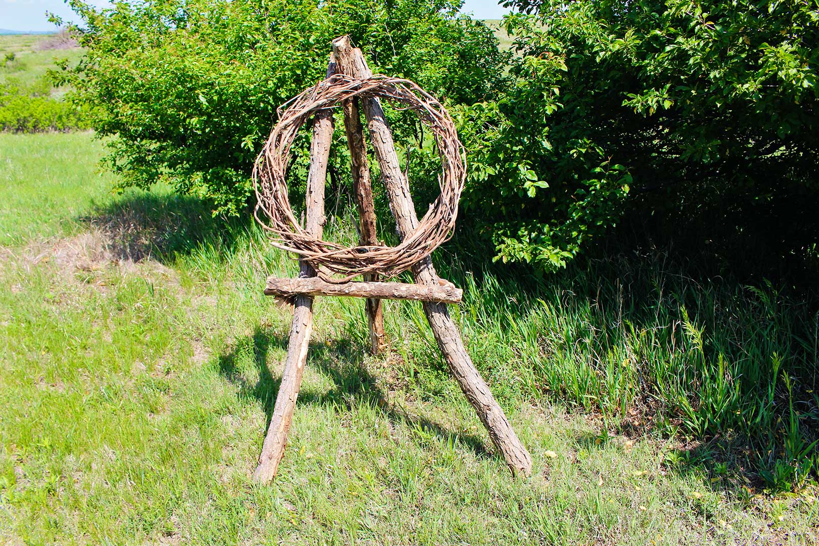 Outdoor large version of the twig easel made from large logs with a wreath resting on it.