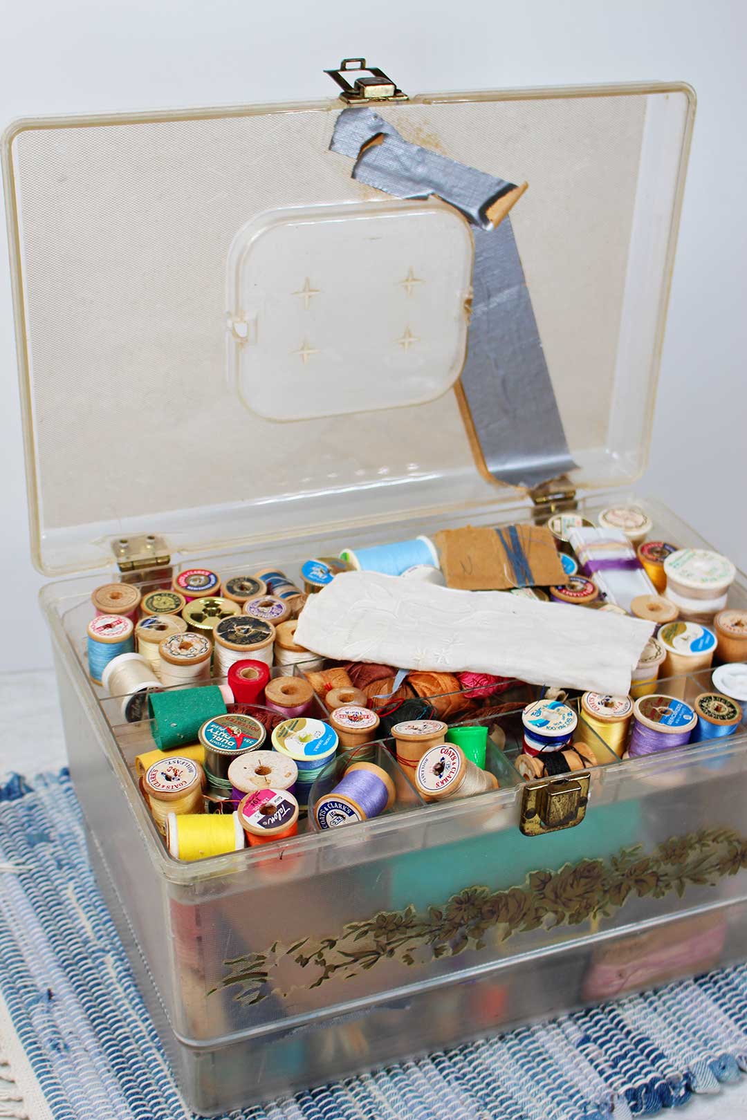 Vintage plastic sewing box with the lid open to show many different colored spools of thread.