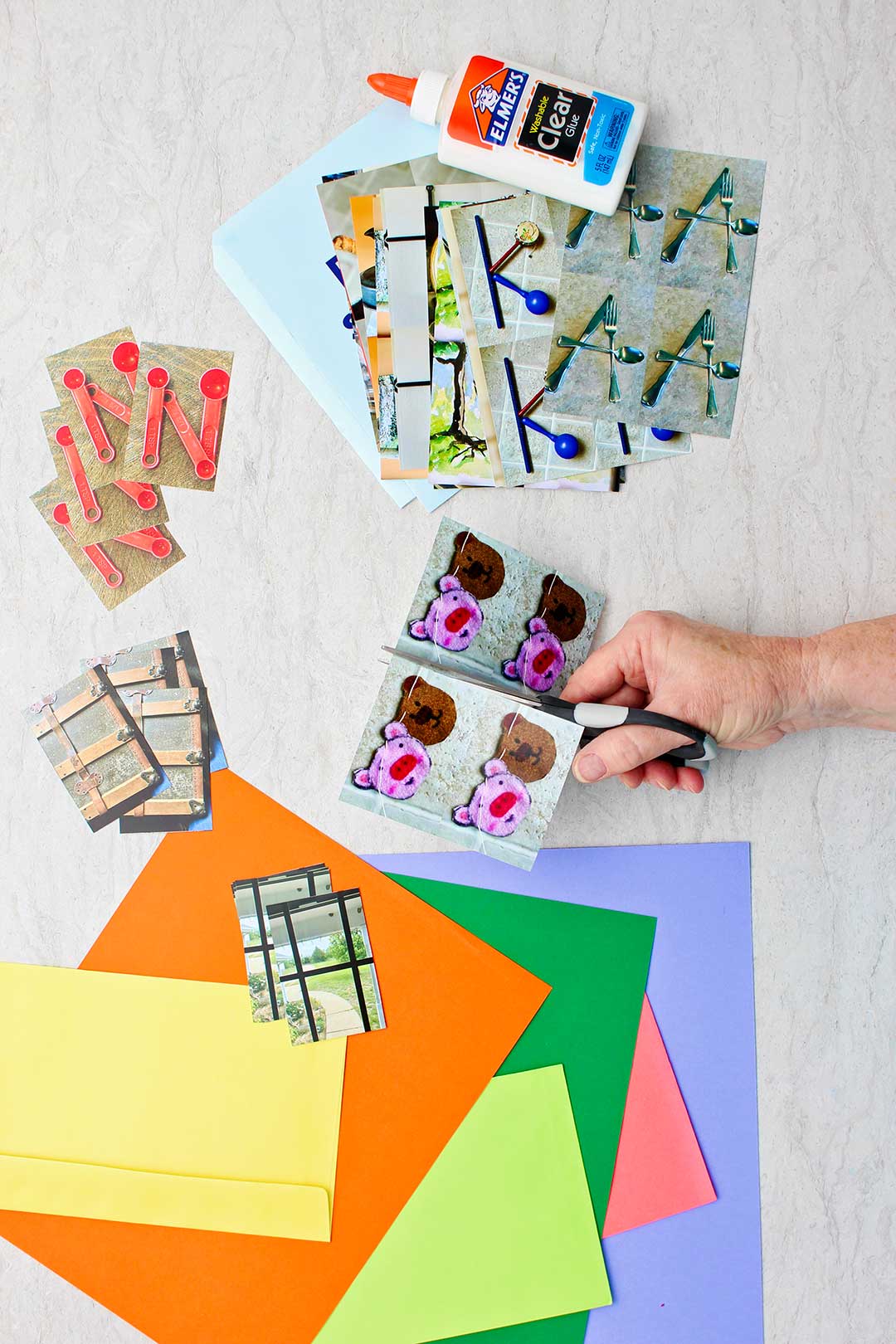 Hand cutting a print out of photo letters with other stacks of prints and colorful paper near by.
