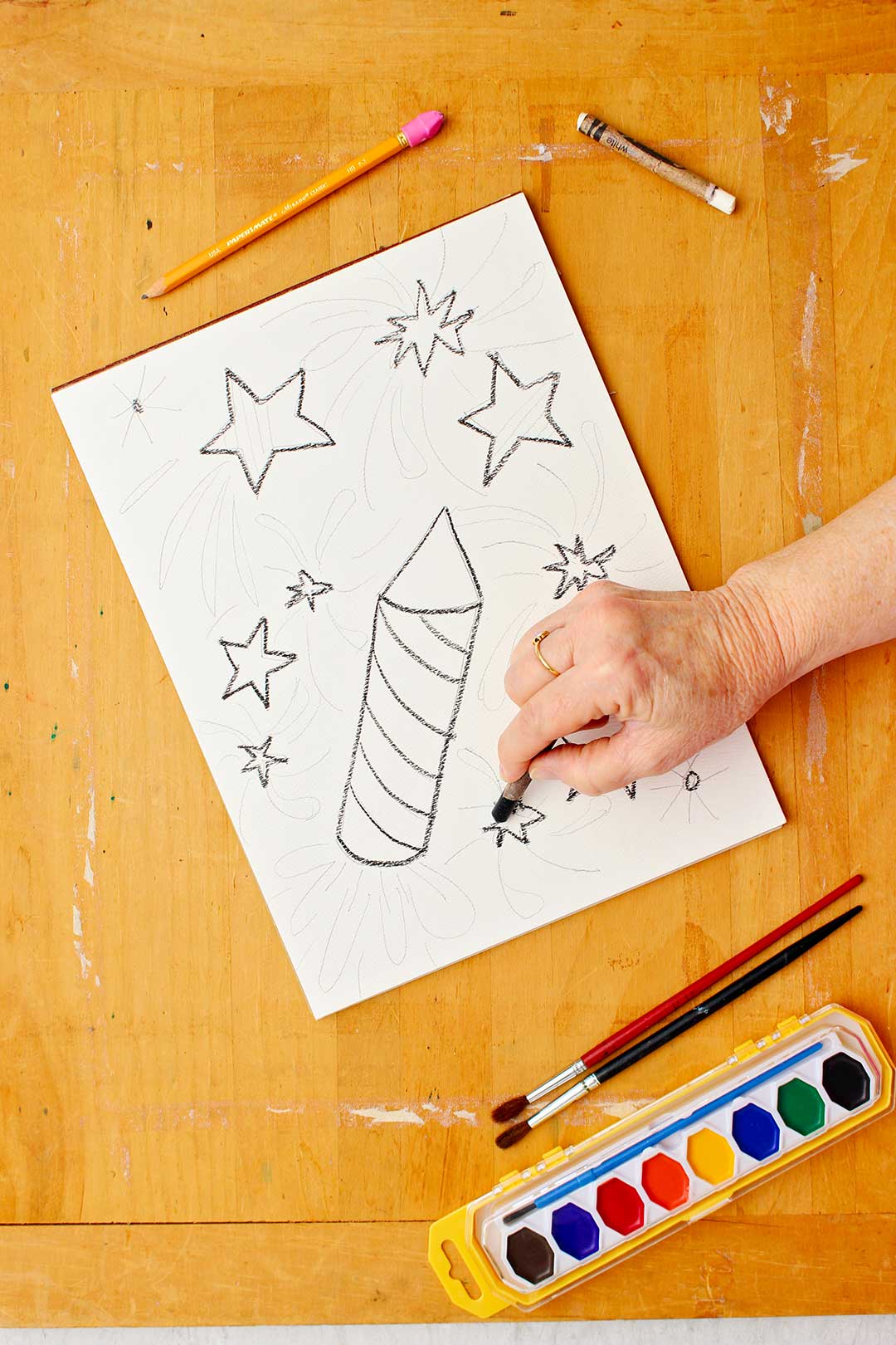 Hand drawing stars with black crayon on paper.
