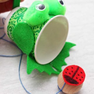 Close up view of completed green frog Ball in Cup Game with ladybug ball.