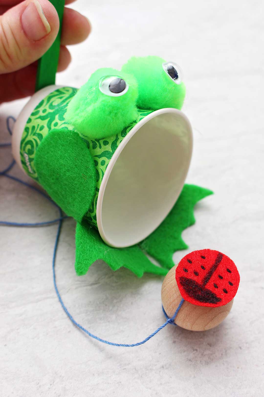 Close up view of completed green frog Ball in Cup Game with ladybug ball.