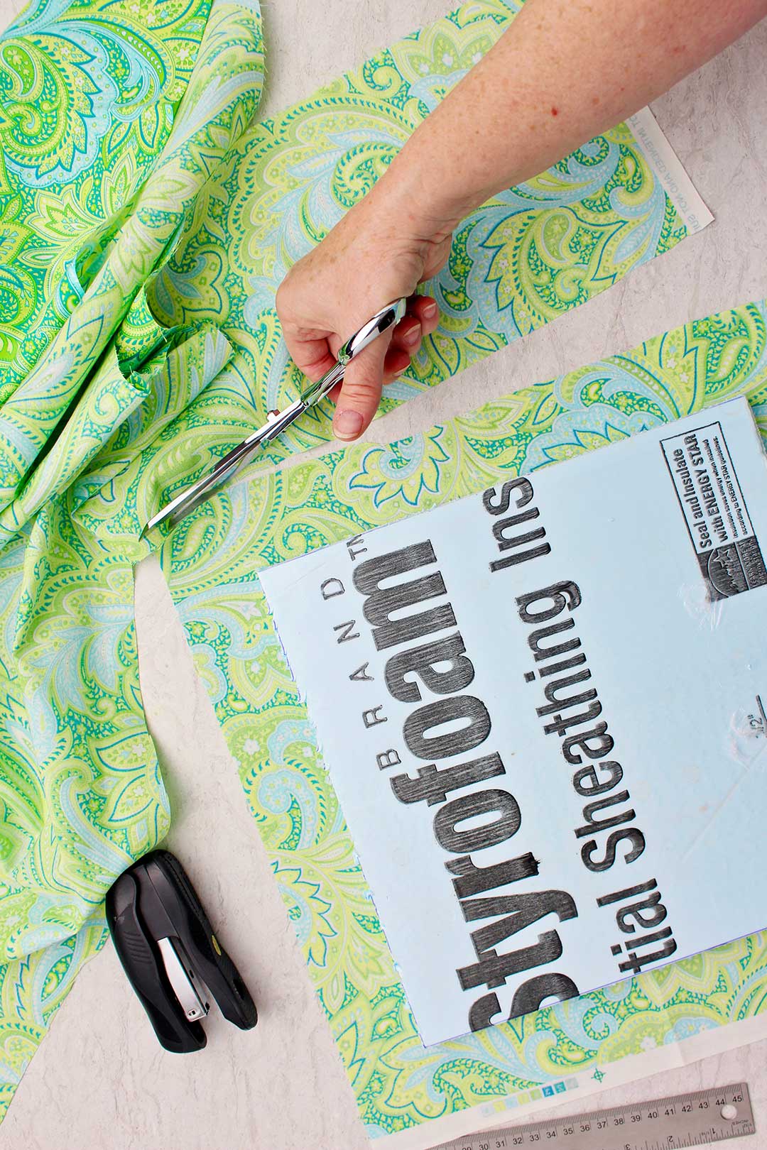 Hand trimming the correct size of green paisley fabric for the foam core bulletin board.