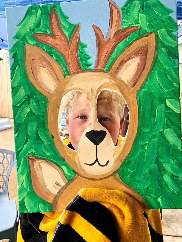Boy with blonde hair holding deer photo frame prop.