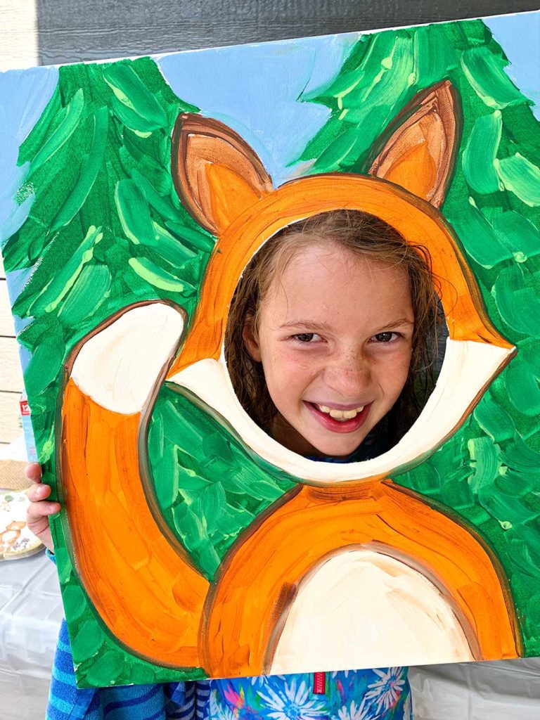 Smiling girl holding on to fox photo frame prop.
