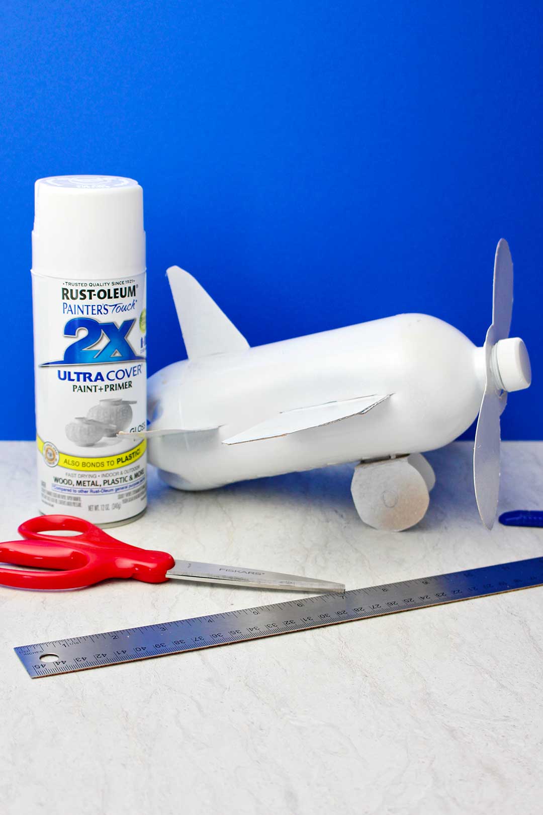 Bottle airplane post white spray painting against blue back drop.