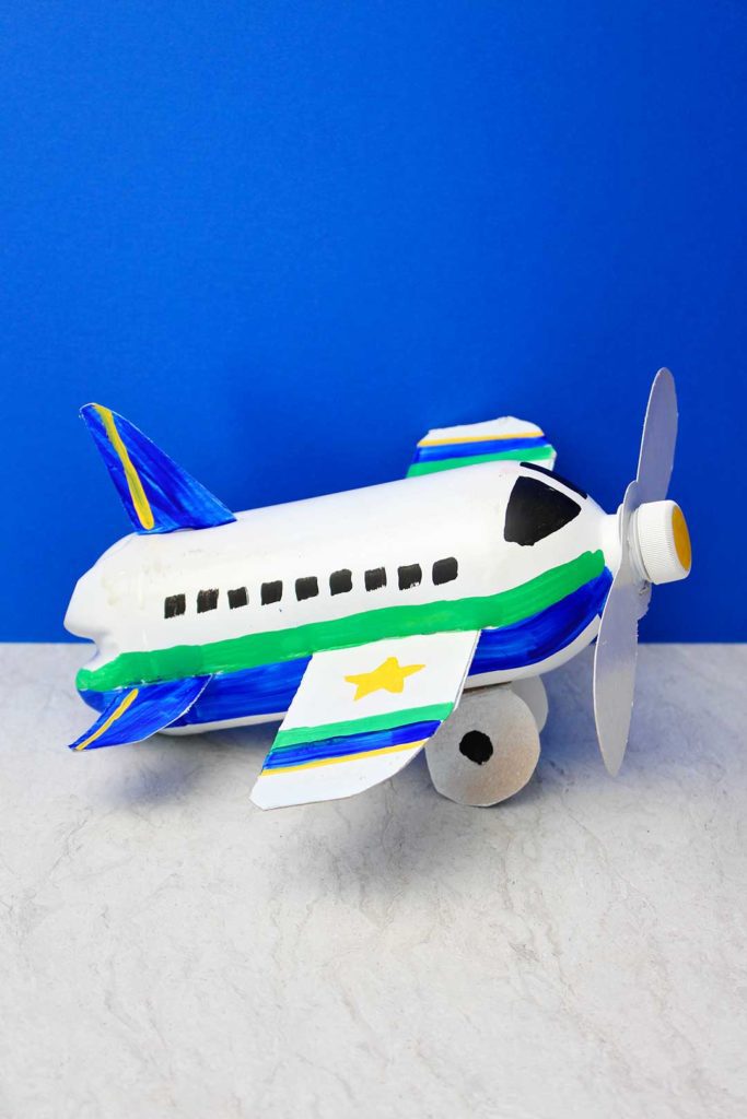 Fully painted and completed airplane bottle craft against a blue backdrop.