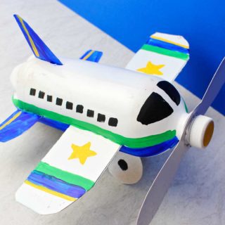 Overhead view of fully painted and completed airplane bottle craft against a blue backdrop.