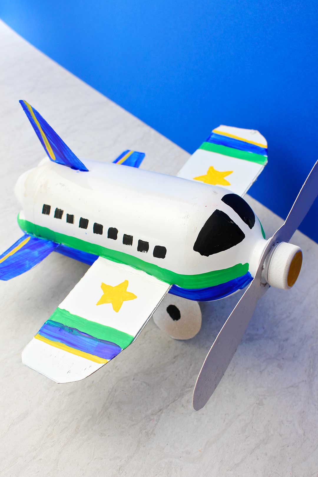 Overhead view of fully painted and completed airplane bottle craft against a blue backdrop.