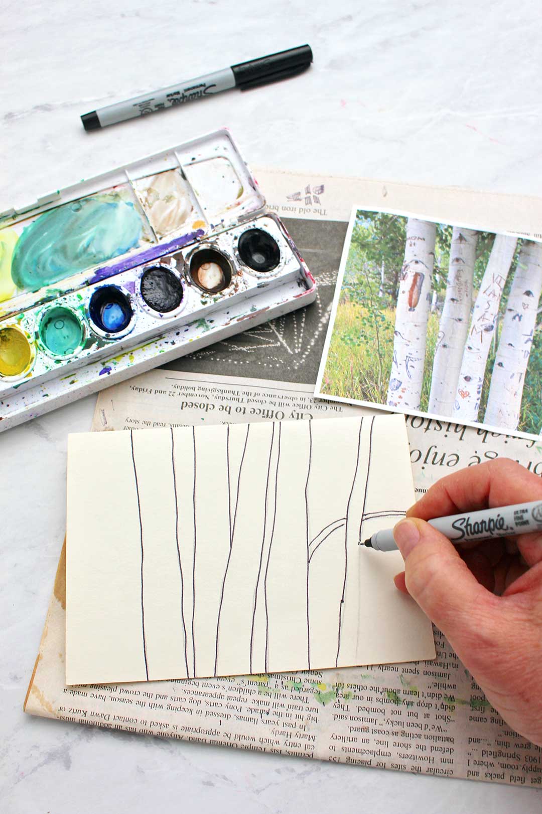 Hand sketching aspen tree trunks with a sharpie marker from an inspiration photo.