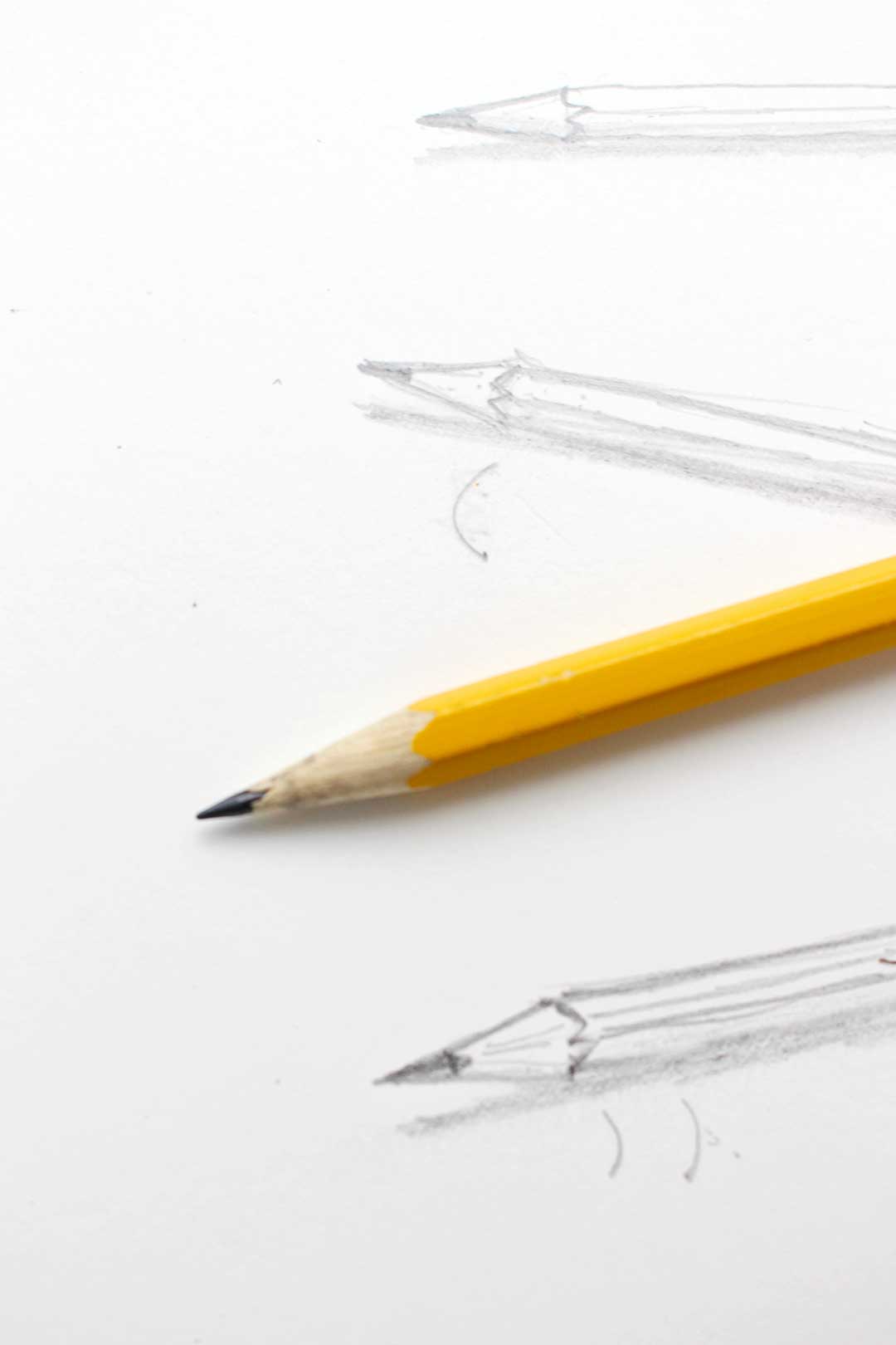 Close up view of the tip of a pencil resting on sketch pad.
