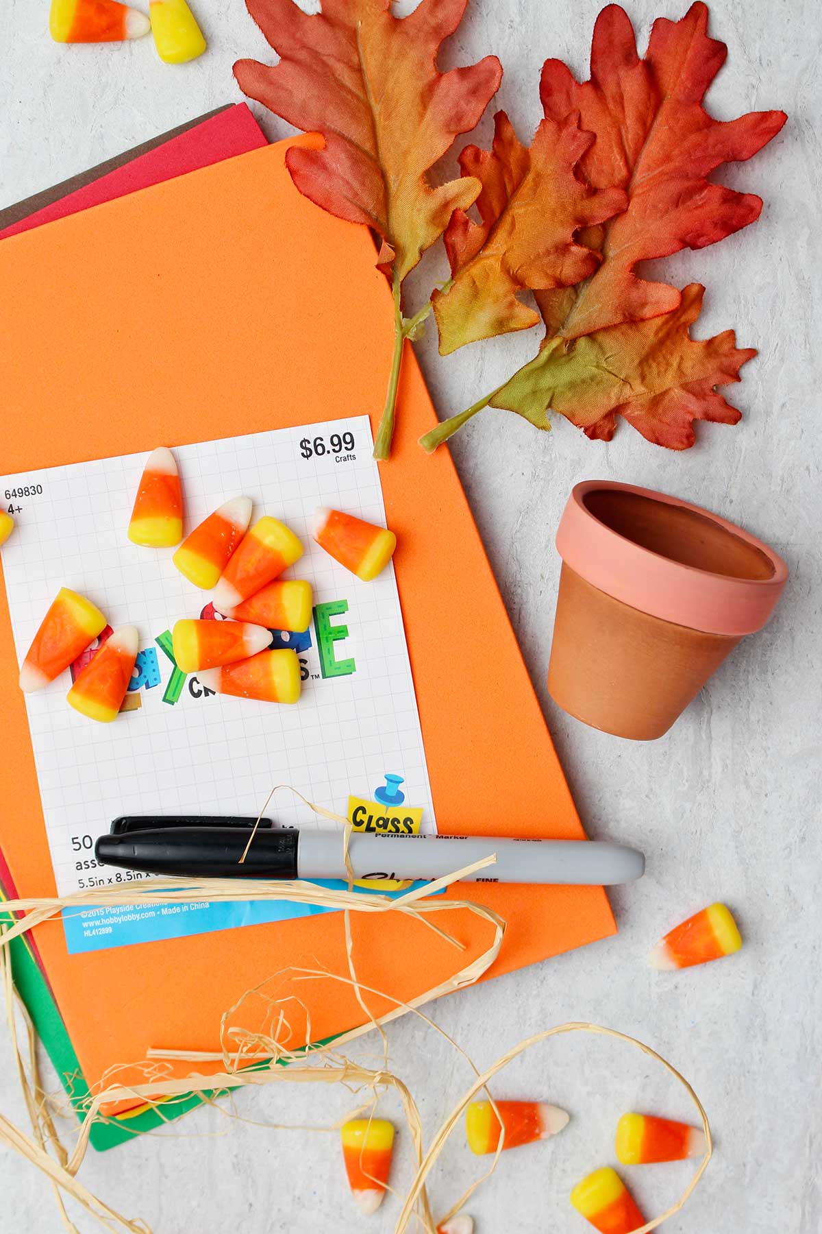 Supplies for Flowerpot Turkey Thanksgiving Favors. Construction paper, fake fall leaves, mini terra cotta flower pot, candy corn and a black sharpie marker.