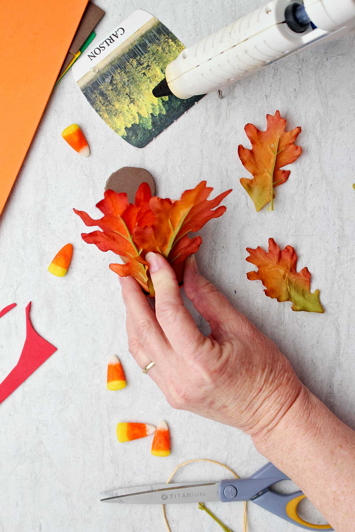 Hand gluing fake fall leaves to the back of the Flowerpot Turkey Thanksgiving Favor (back view)