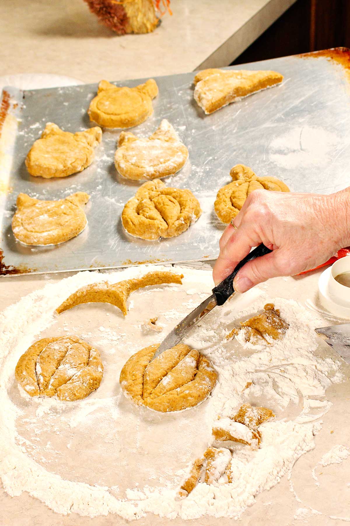 Hand cutting designs in scone dough to resemble a pumpkin before baking.