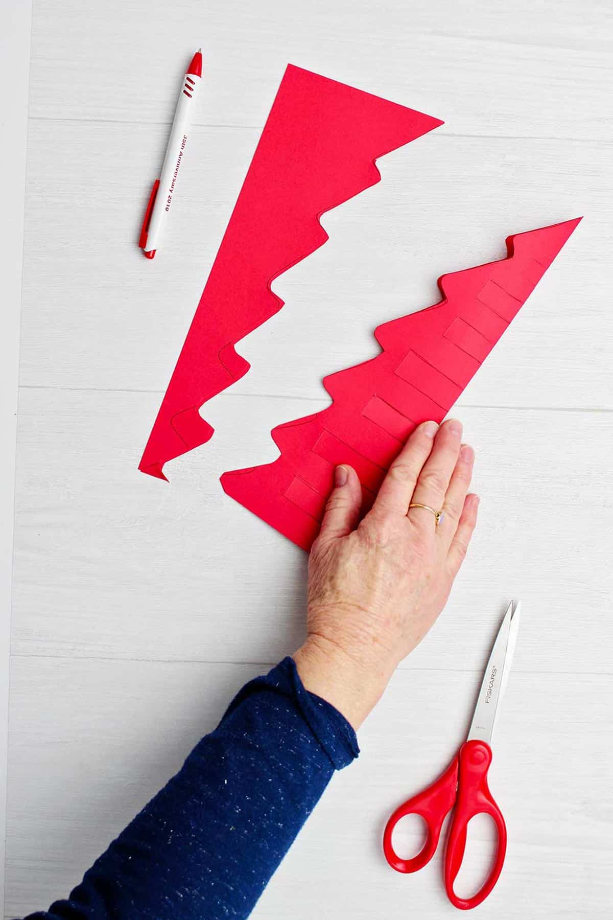 Red tree cut out folded in half with pen drawn areas to cut out.