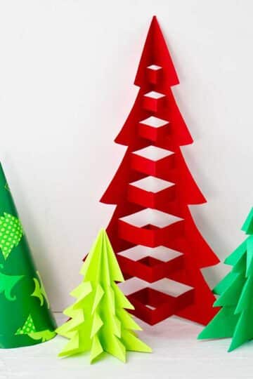 Four finished origami trees of different heights in red, green and patterned tree paper .