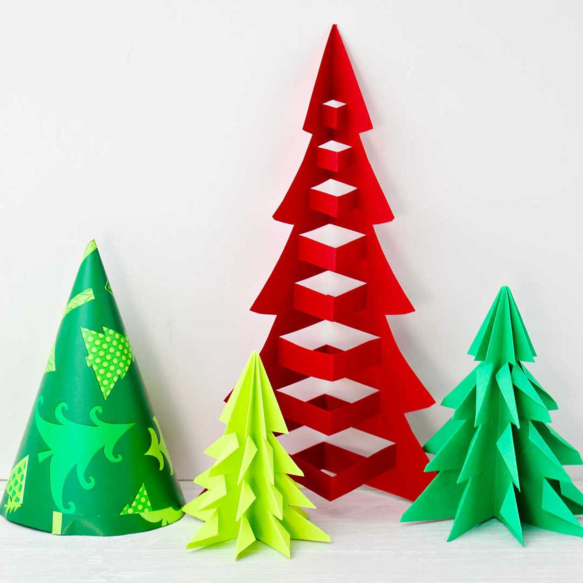 Four finished origami trees of different heights in red, green and patterned tree paper .
