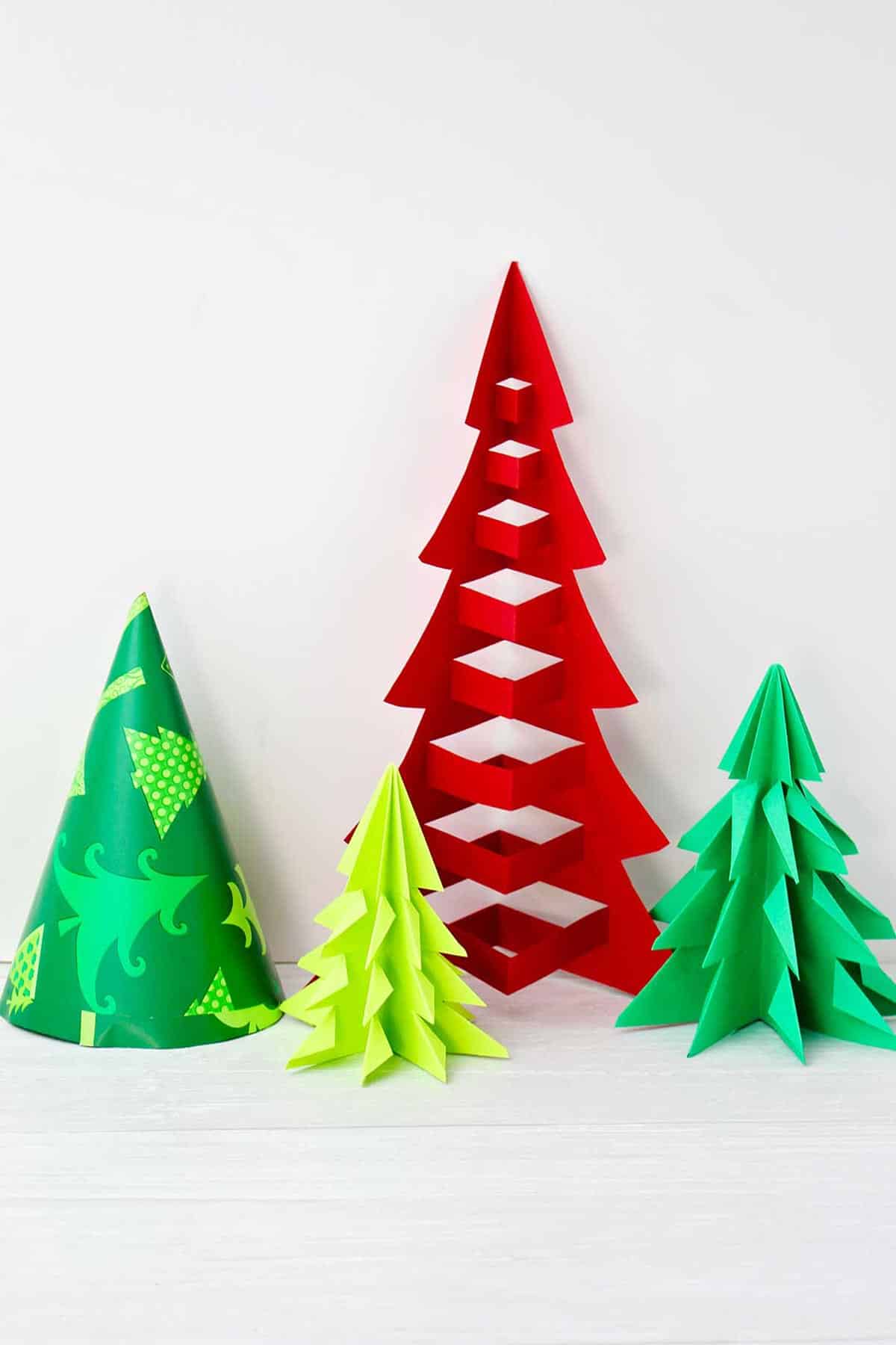 Four finished origami trees of different heights in red, green and patterned tree paper .