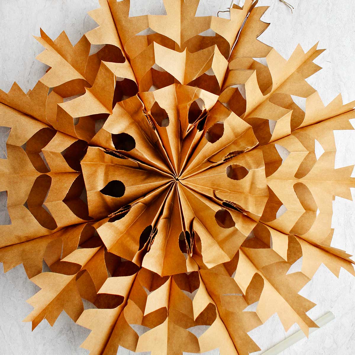Square image of completed brown paper bag snowflake.
