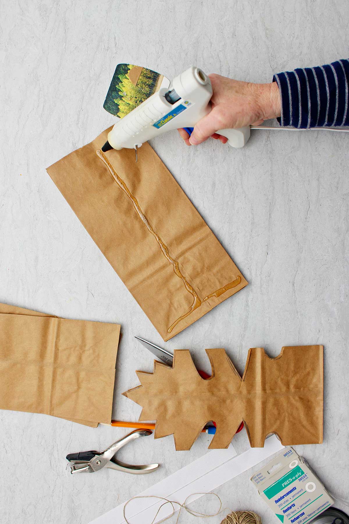 Hand hot gluing brown paper bags together before cutting.