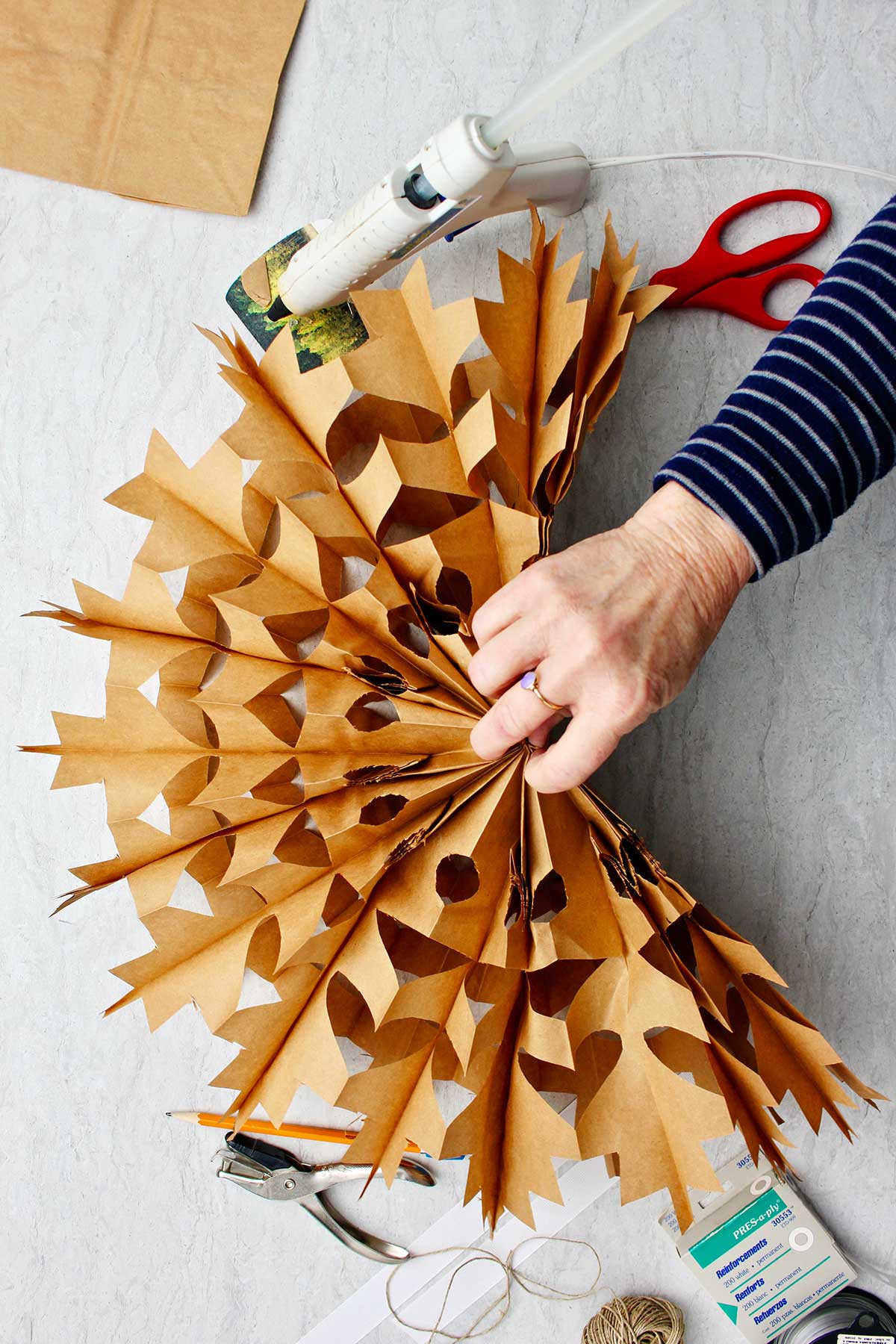 Hand unfolding the brown paper bag snowflake.
