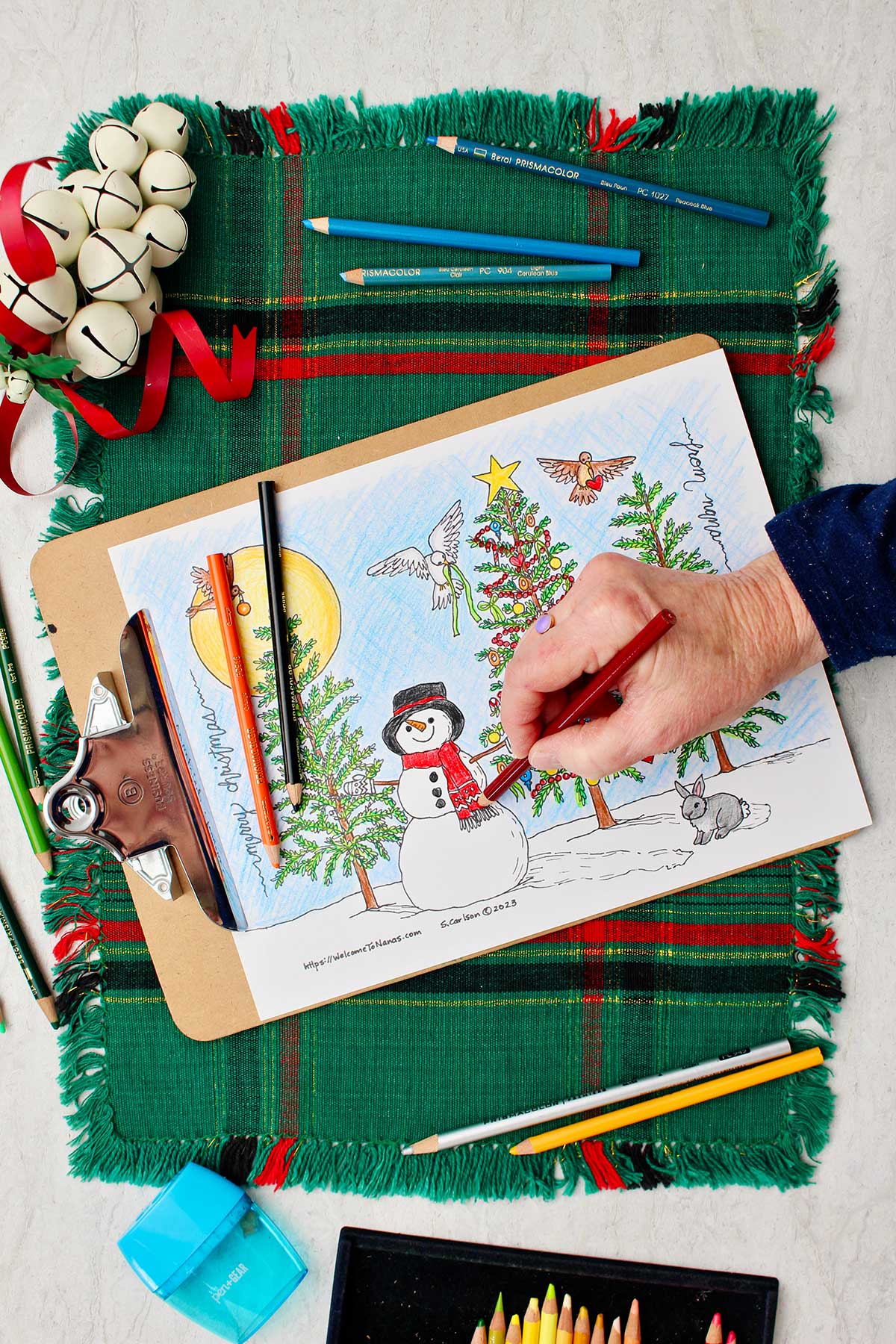 Hand coloring the snowman scarf red on the Christmas tree coloring page.