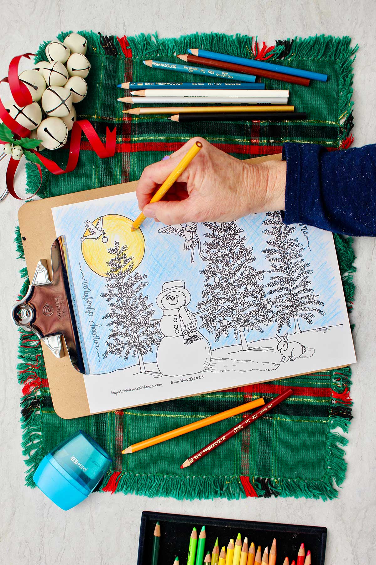 Hand coloring in sun yellow on partially colored Christmas tree coloring sheet.