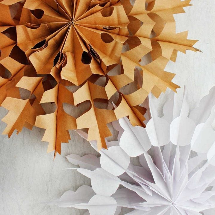 Two completed paper bag snowflake. One in brown and one in white.