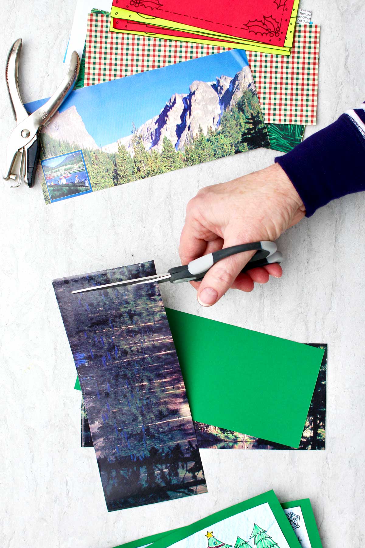 Someone cutting a magazine page into a rectangle, with colorful paper and other magazine page cutouts nearby.