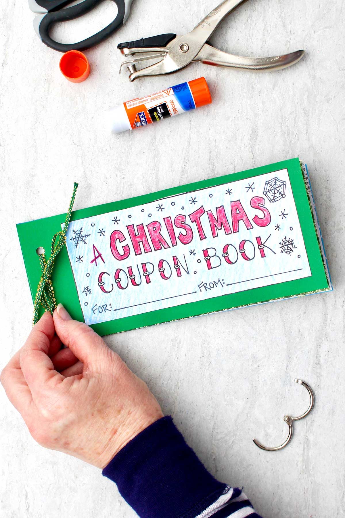 A finished printed and decorated Christmas coupon book tied together with green string.