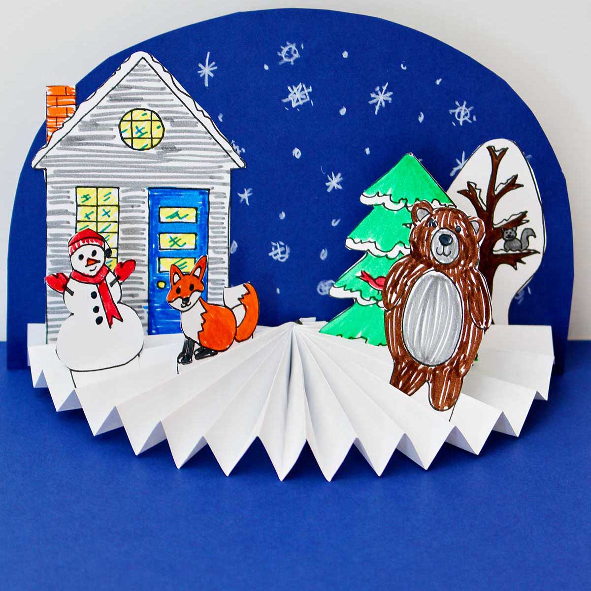 Completed Easy Paper Fan Craft in a winter theme with a snowman, fox, bear and snowy blue background. Square Image.