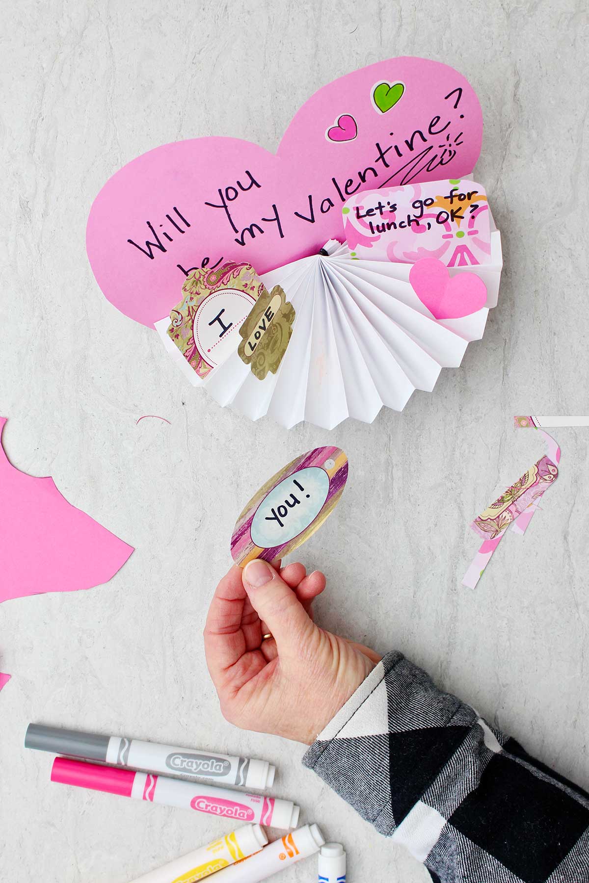 Little love notes being glued into folds of Valentine's Day themed fan.