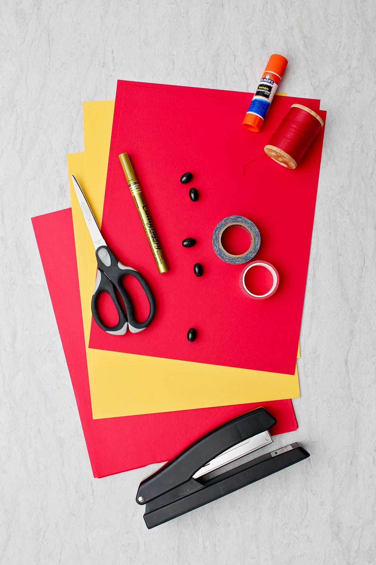 Supplies to make Simple Chinese Lanterns. Red and yellow paper, scissors, gold pen, tape, string, glue and stapler.