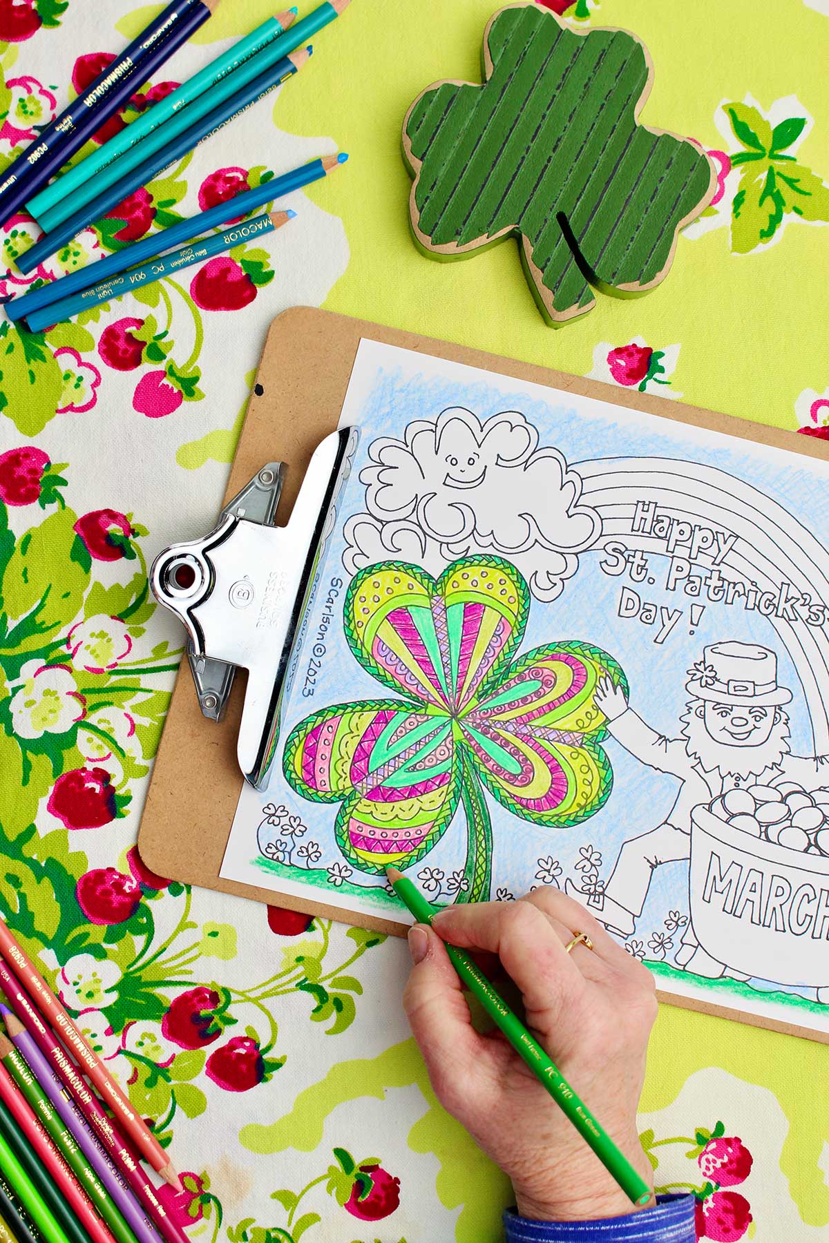 Hand coloring shamrock green on St. Patrick's Day coloring page.