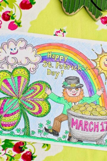 Completed St. Patrick's Day coloring page sitting on a green table cloth with strawberries on it.