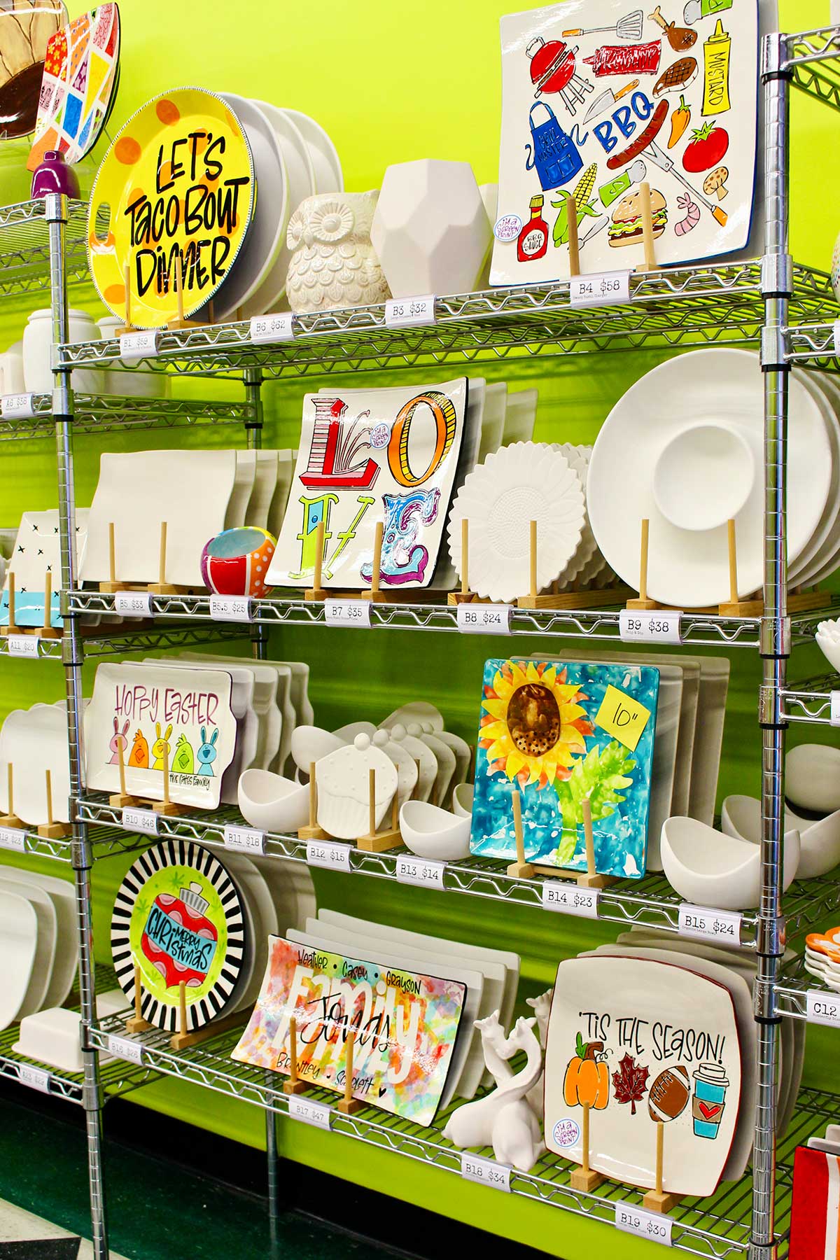 A display of larger plate options on metal rack at ceramic painting studio.