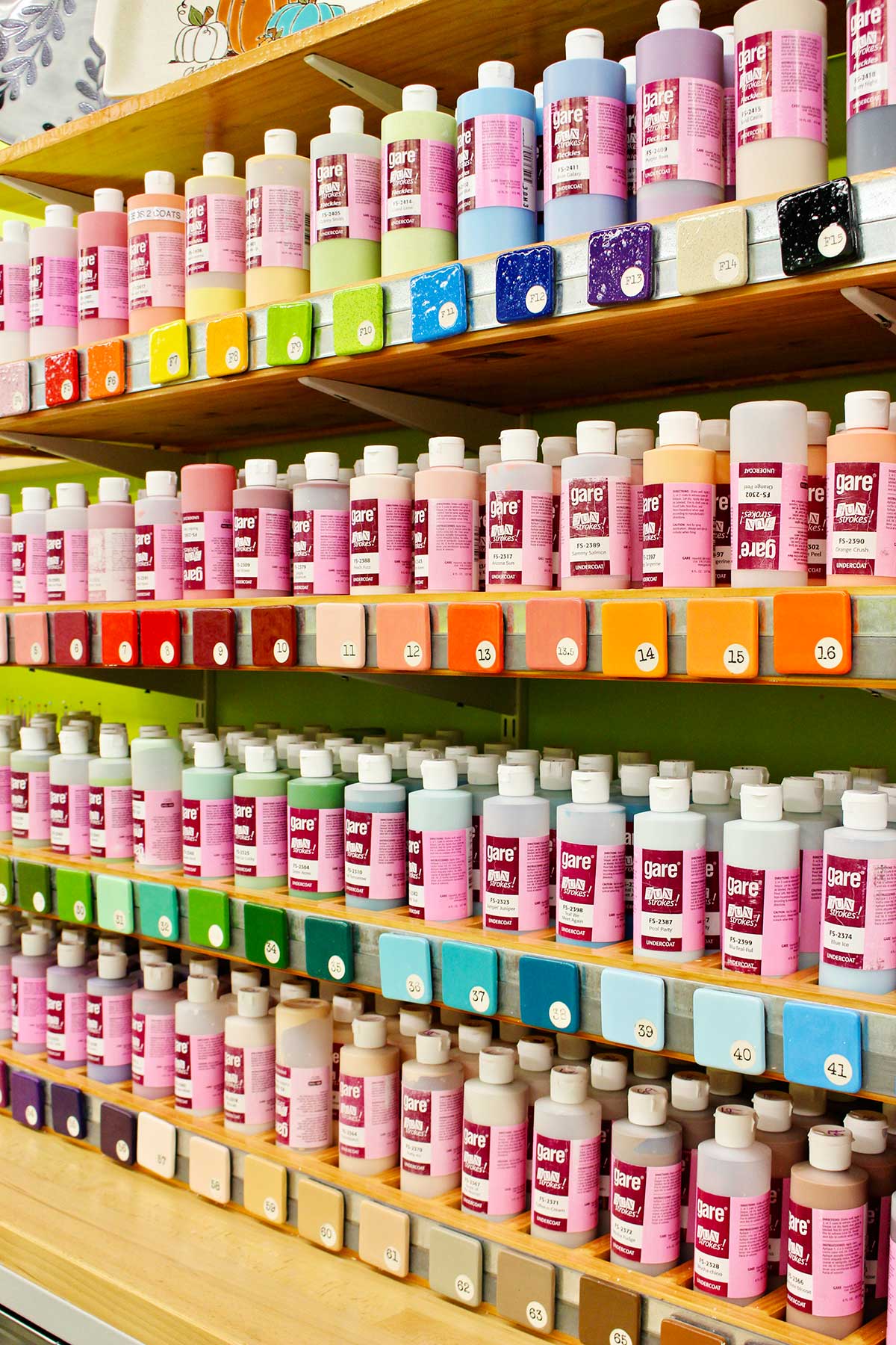 A display of large paint bottles with samples color tiles at ceramic painting studio.
