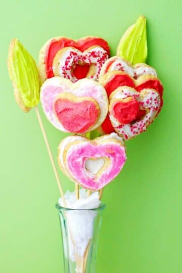 Close up image of a completed sugar cookie bouquet in a vase against a green backdrop.